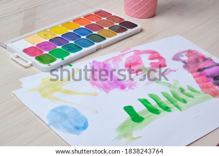 watercolor paints and drawing of a small child on a wooden light table