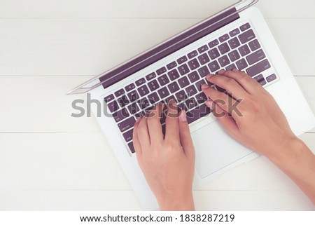 Hand of man working on laptop computer on wooden table at office, male typing on notebook on desk at home, flat lay, copy space, above, top view, minimal modern, business and communication concept.