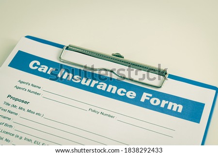 Car Insurance Claim Form or Auto Insurance Document on Right Slant and Clipboard on White Office Table in Vintage Tone