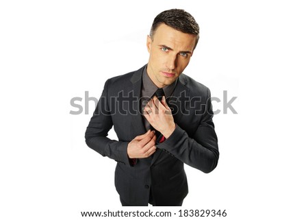 Confident businessman standing and tying his tie isolated on a white background