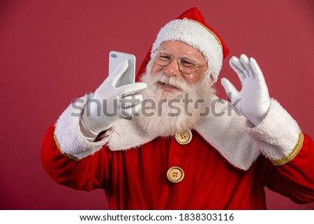 Stylish trendy grandfather aged mature Santa tradition winter costume headwear spectacles white beard take christmastime selfie picture front camera in red background.