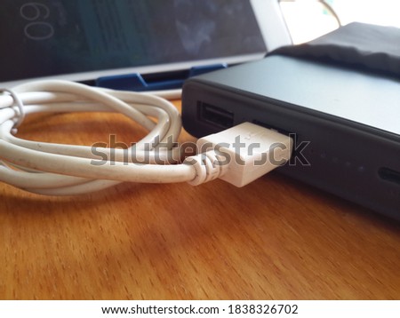 Clous-up image of power bank charging cable wooden table background