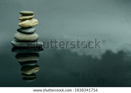 Isolated balanced stack of rock with it's reflection on dark glass