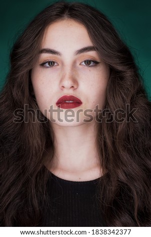 Portrait of a young brunette with lush wavy hair and beautiful highlights in the eyes