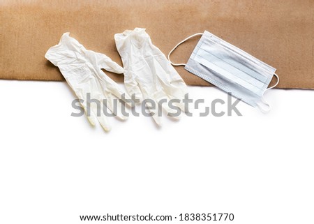 Protection concept. Pair of latex medical gloves and surgical ear-loop mask on white and brown background.  For quarantine isolation