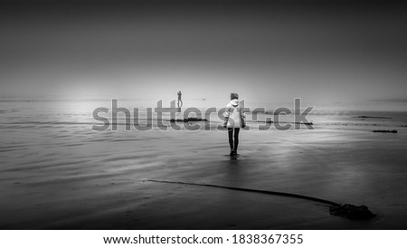 Black and White Photo of a Woman walking in Dense Fog on the Sandy Beach in Cox Bay at the Pacific Rim National Park on Vancouver Island, British Columbia, Canada