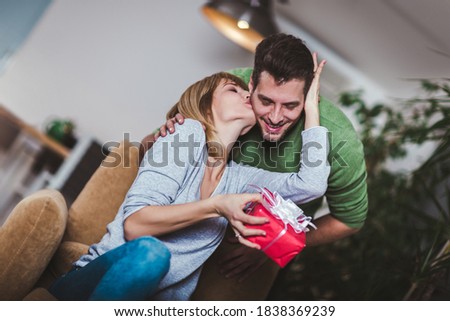 Man giving a surprise gift to woman at home. Selective focus.