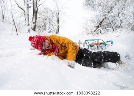 The boy fell while driving off the hill on a sled. Winter recreation for children in nature.
