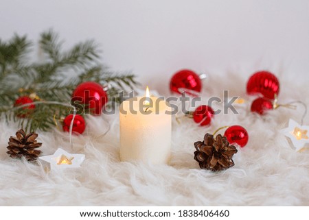 Christmas background, red Christmas toys , beads and a burning candle. Greeting card with Christmas