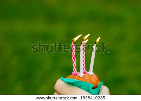 Mini cupcake with four candle for four year anniversary isolated on green background.Anniversary celebration.Congratulations card. Burning candles.Copy space