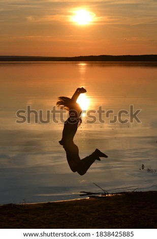 Girl jumping on the beach. A woman dances against the sunset. Setting sun over the sea.  A person enjoys a vacation. 