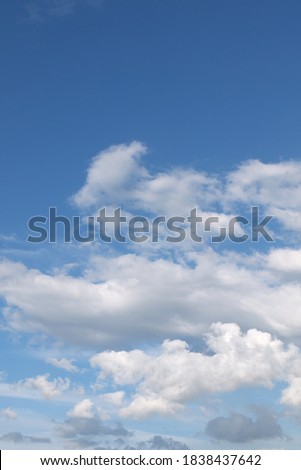 Blue sky with dramatic cumulus and cumulonimbus clouds. Blue gradient. Nature sky background, texture for design. Vertical photo. Copy space.
