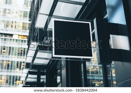 Black square signboard with blank space for your logo on the wall of a modern shopping center, mockup