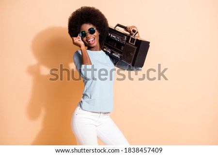 Photo portrait of african american girl holding boombox eyewear isolated on pastel beige colored background