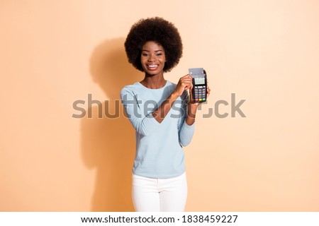 Photo portrait of curly dark skinned girl put credit card to bank terminal doing cashless purchase isolated on beige color background