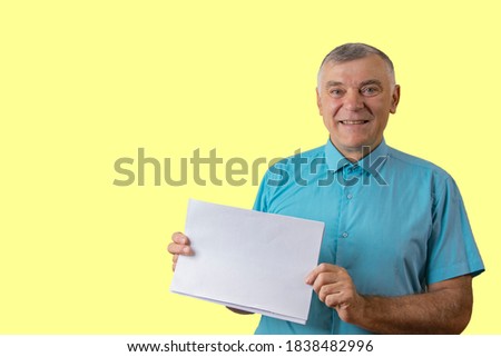 Smiling man holding blank white sheet for text. Isolated on yellow background.