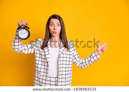 Photo of impressed funny brown hair woman plaid jacket hold bell pointing empty space isolated yellow color background