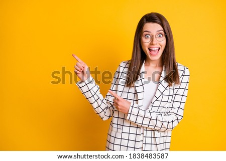 Photo of shocked student woman wear plaid jacket pointing empty space two fingers isolated yellow color background