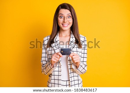 Photo portrait of cheerful funny business woman staring holding plastic bank card isolated on vibrant yellow color background