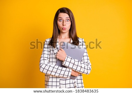 Photo portrait of shocked amazed girl keeping hugging computer staring wearing checkered suit isolated on bright yellow color background