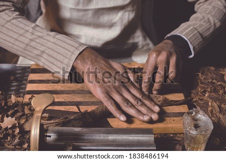 Process of making traditional cigars from tobacco leaves with hands using a mechanical device and press. Leaves of tobacco for making cigars. Close up of men's hands making cigars. Royalty-Free Stock Photo #1838486194