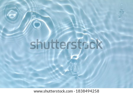 De-focused blurred transparent blue colored clear calm water surface texture with splashes and bubbles. Trendy abstract nature background. Water waves in sunlight with copy space. Royalty-Free Stock Photo #1838494258