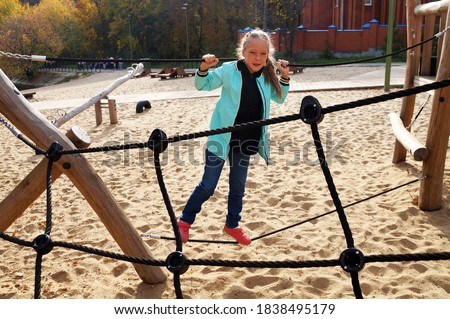 little girl climbing rope ladder on the playground in the park