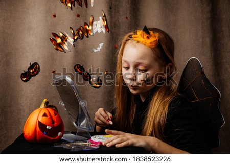a girl is preparing for Halloween, doing her makeup in front of a mirror