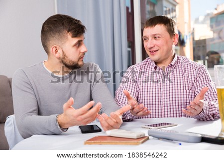 Two cheerful men enjoying conversation at home table