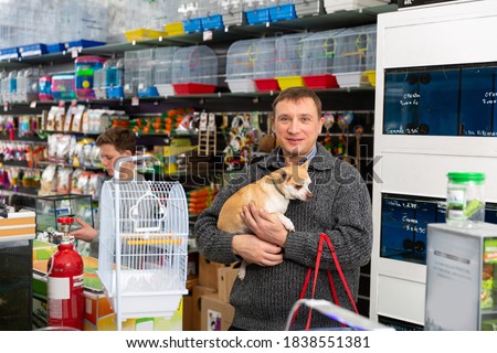 Portrait of adult man with dog in petshop, boy on background. High quality photo