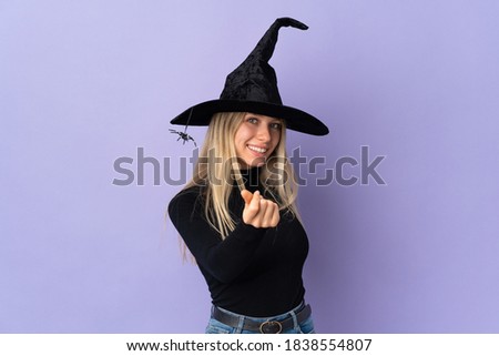 Young woman with witch costume over isolated background making money gesture
