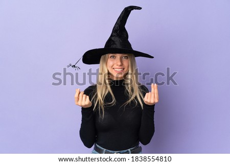 Young woman with witch costume over isolated background making money gesture