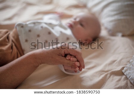 Mother holding infant baby, take care of her 3 months old child at home bedroom . Happy mom carying of her newborn son . Mum love little baby