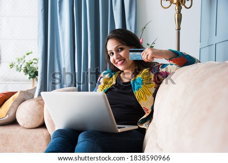 Indian pretty woman or girl using debit or credit card for online shopping on laptop computer