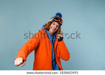 Caucasian joyful sportsman smiling and dancing on camera isolated over blue background
