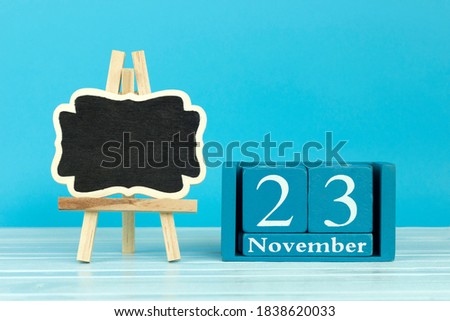 wooden calendar with the date of October 23 and an easel on a blue background, place for text