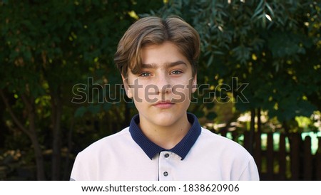 Young beautiful Caucasian boy calmly looks at the camera. Street portrait, calm emotions. Royalty-Free Stock Photo #1838620906