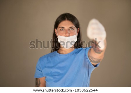 Doctor wearing a face mask passing a medical glove to a person