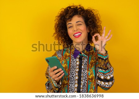 Portrait of a pretty happy Caucasian young woman dressed in generic design shirt taking a selfie isolated over bright background