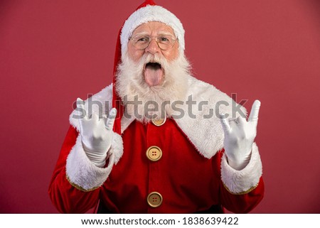 Santa Claus making rock n roll sign with hands and red background.