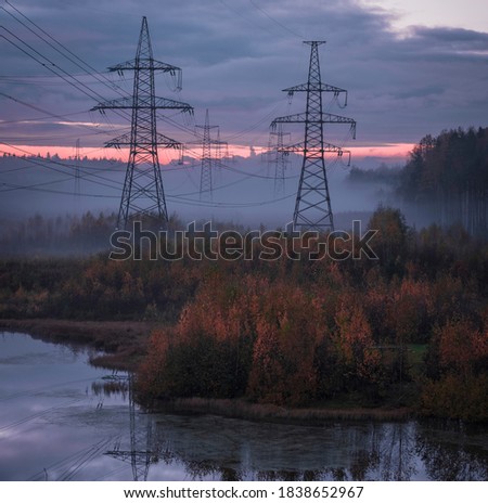 Power lines in fog over an autumn lake in the forest