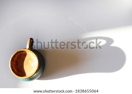 Coffee creams in the form of a yin-yang siluete, in an authentic cup of espresso coffee, on a white table background with a shadow from the cup. Good morning.Concept with place for your text. Top view Royalty-Free Stock Photo #1838655064
