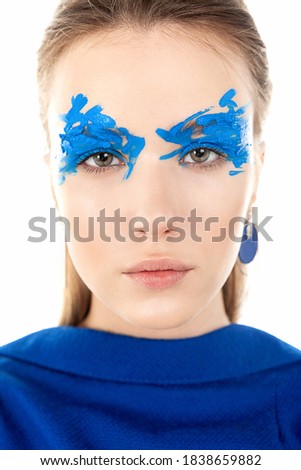 Close-up portrait of a girl with graphic bright blue eye makeup. Art make-up.