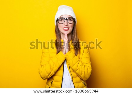 Friendly young woman meditates in a yellow jacket on a yellow background.