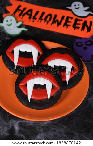 Vampire fangs protruding from scarlet lips, Glazed honey gingerbread cookies. Halloween food idea