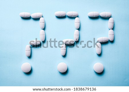 question mark made of white pills on a blue background. treatment choice and idea and question concept.