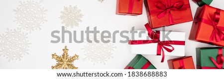 panoramic concept of multicolored gift boxes and decorative snowflakes on white background
