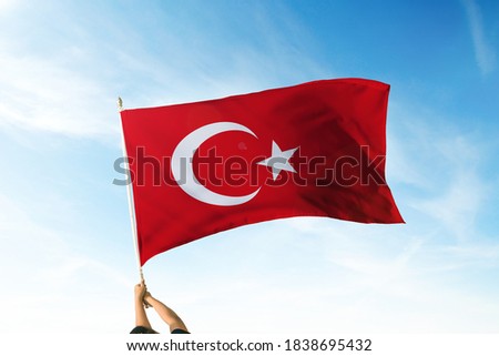 Turkey flag holding hands in the air. Blue Sky Flag