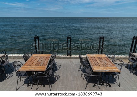 Range of wooden table and black chair for relaxation at restaurant near sea 