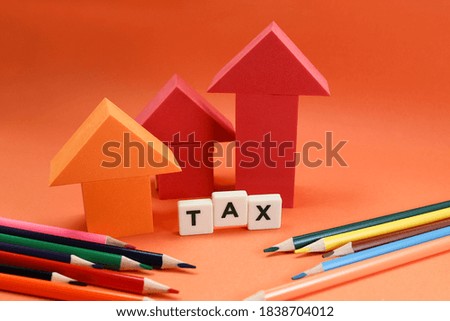Block letters on tax with arrows and colorful pencils on orange background 